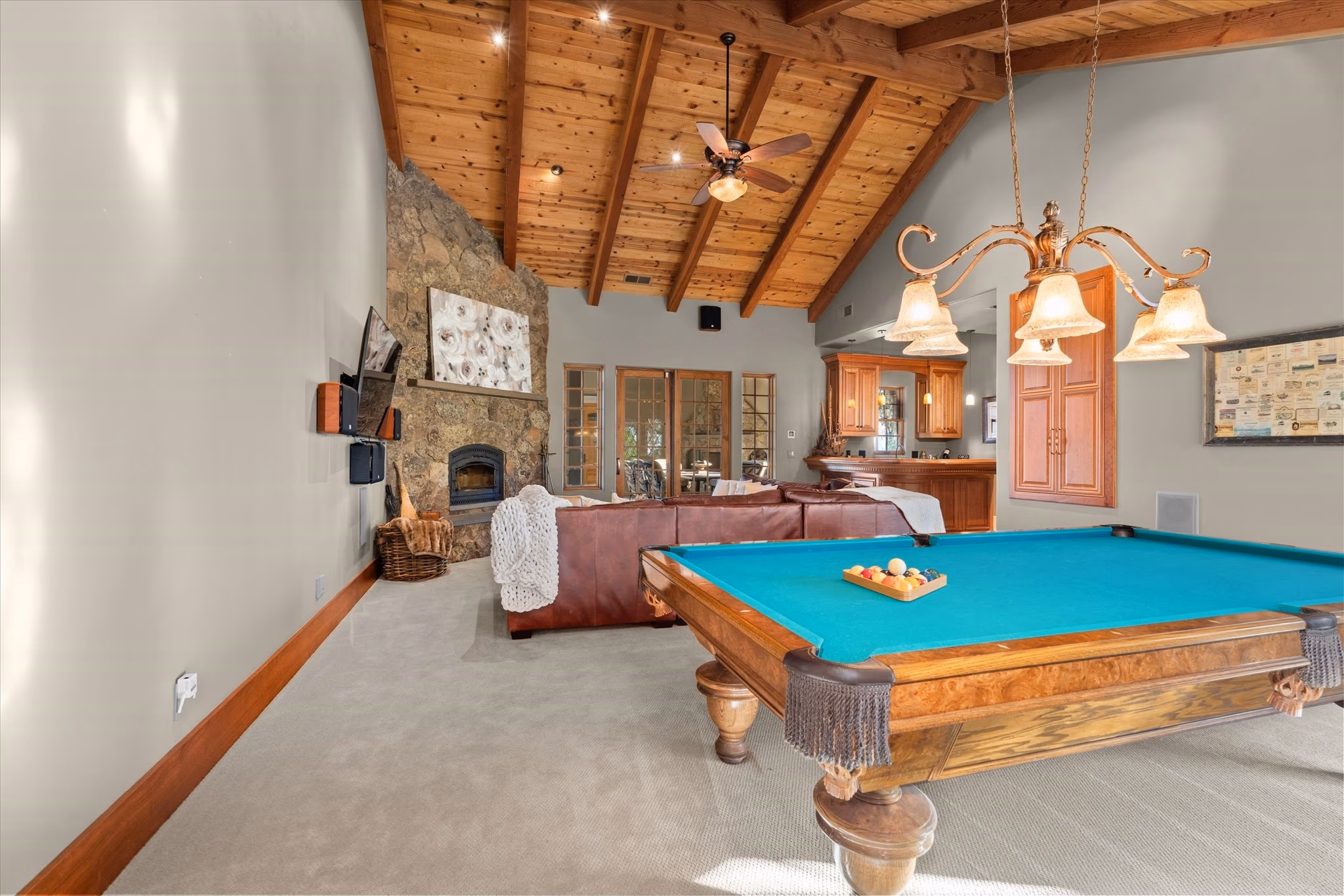 The lower-level lounge, with a billiard table, a stone fireplace, a beamed cathedral ceiling and a bar at the far end.