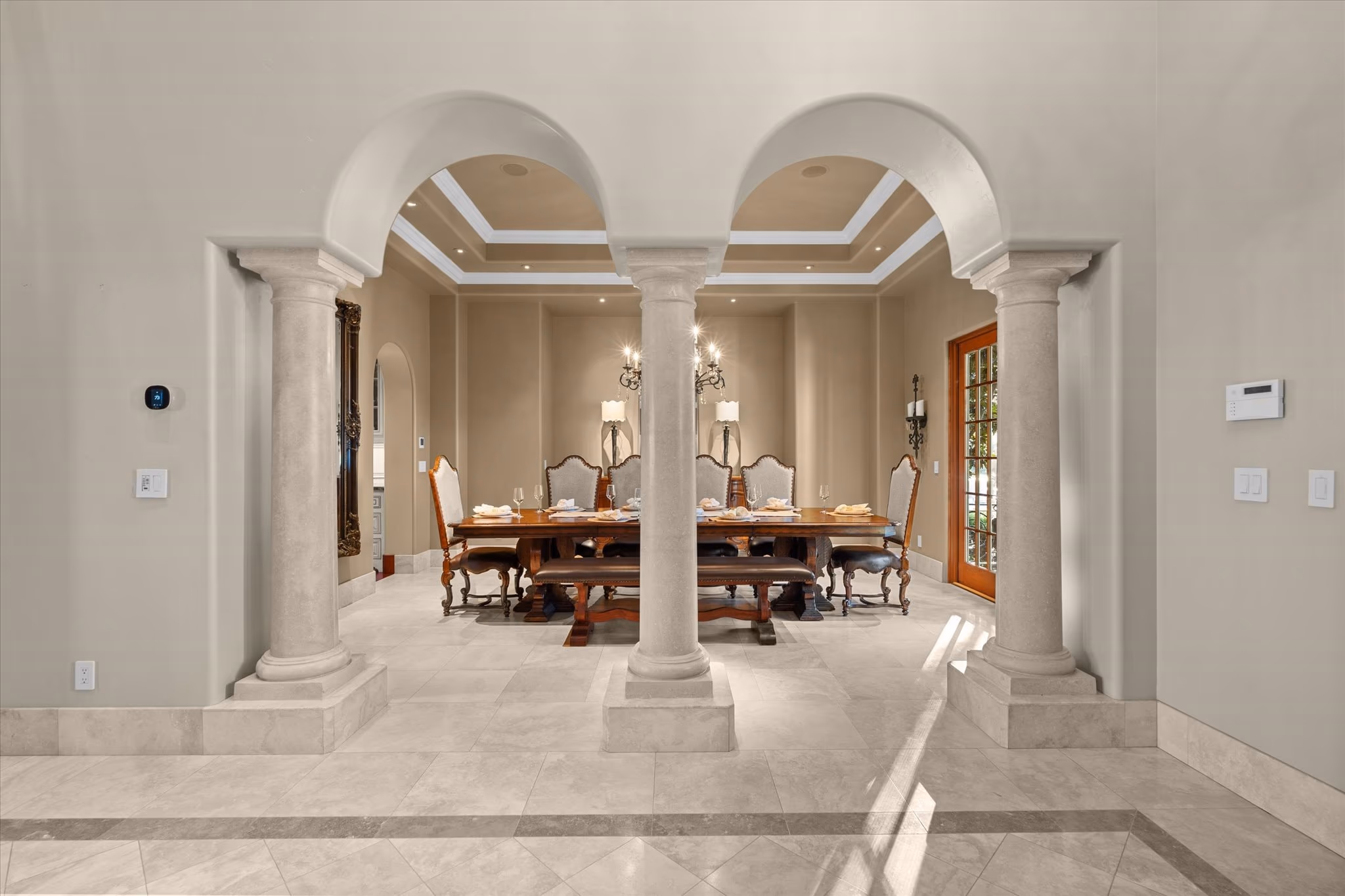The formal dining room, with a long table set for eight, a tray ceiling, a chandelier and a leaded window.