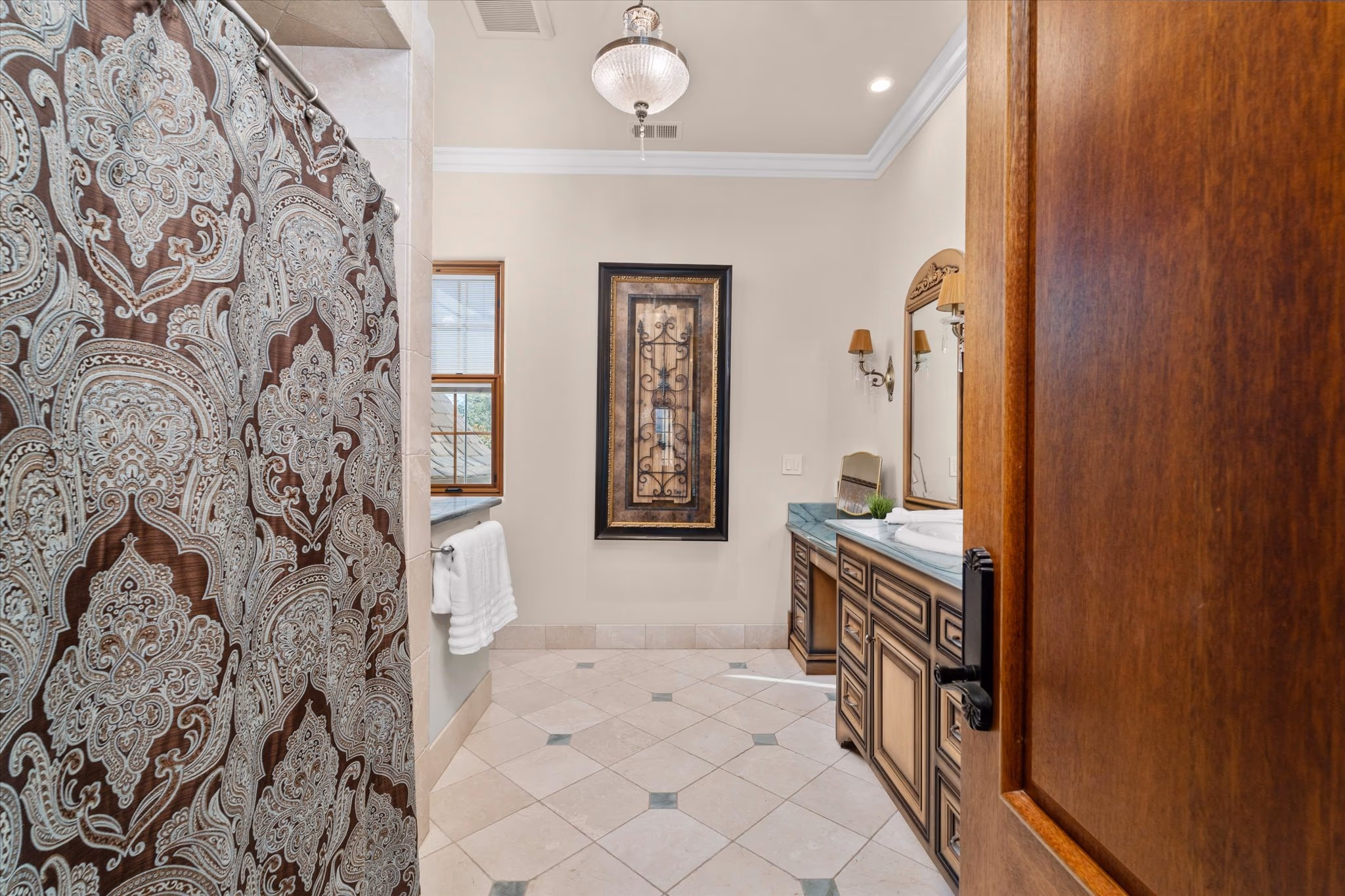 A guest bathroom, with a stone vanity, a framed mirror and a tiled shower.