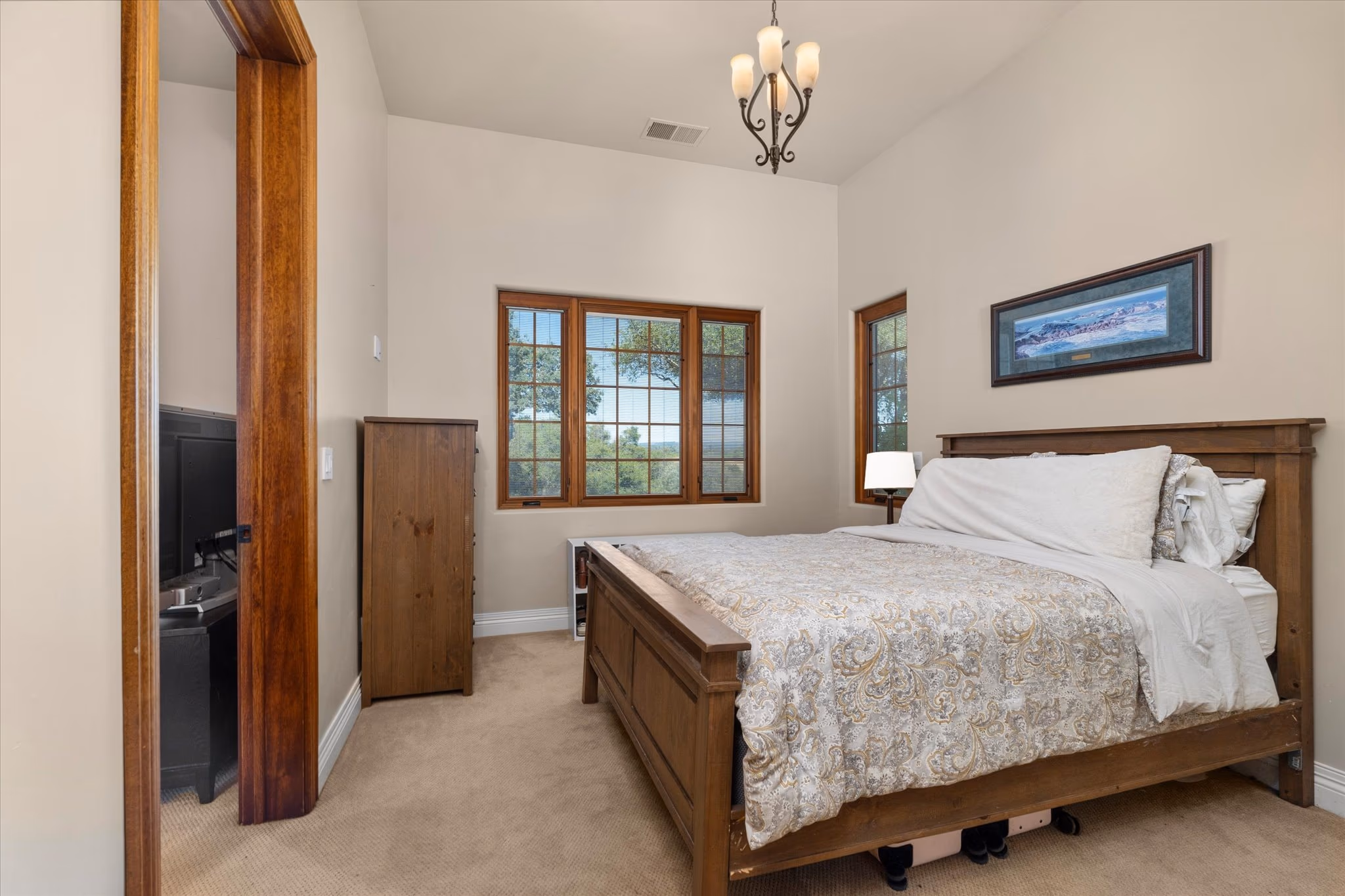 A bedroom in the attached guest house, with a timber bed, exposed beam and a window to the grounds.