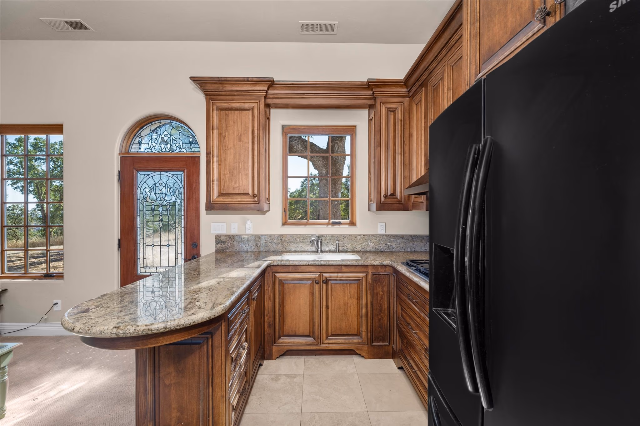 The kitchen of the attached guest house, with cherry cabinetry, granite counters and an arched window over the sink.