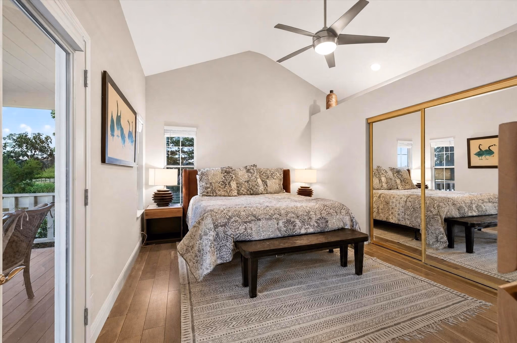 The primary bedroom of the lake house, with a vaulted ceiling and a door to the garden.