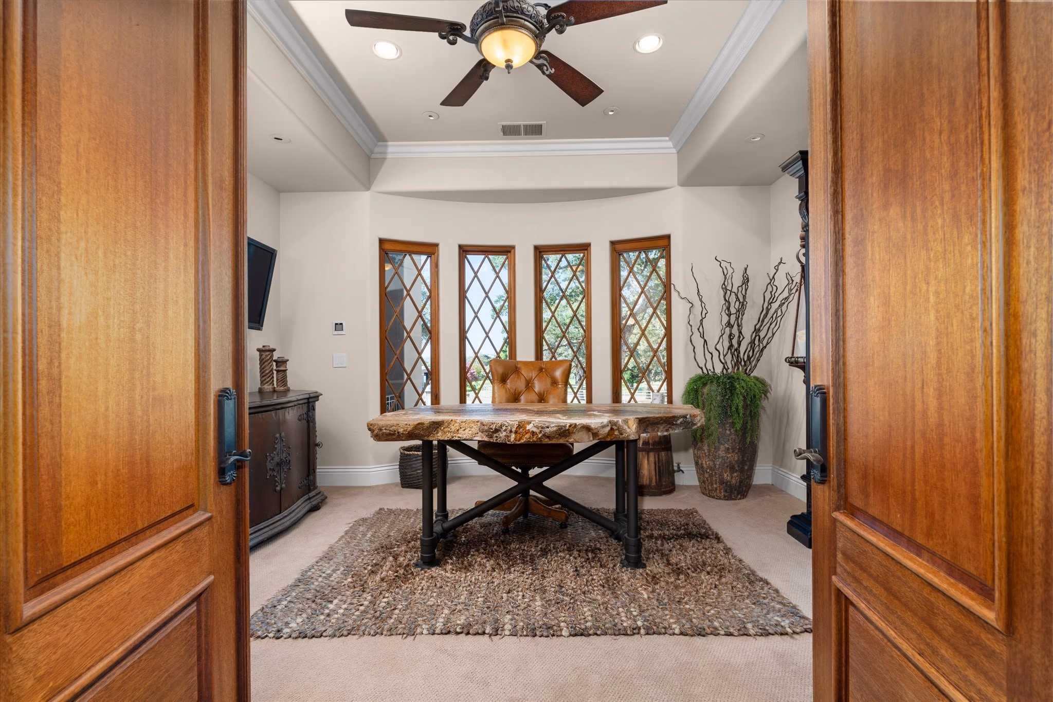 An office in the main residence, with a live-edge timber desk set into a bay of leaded windows.