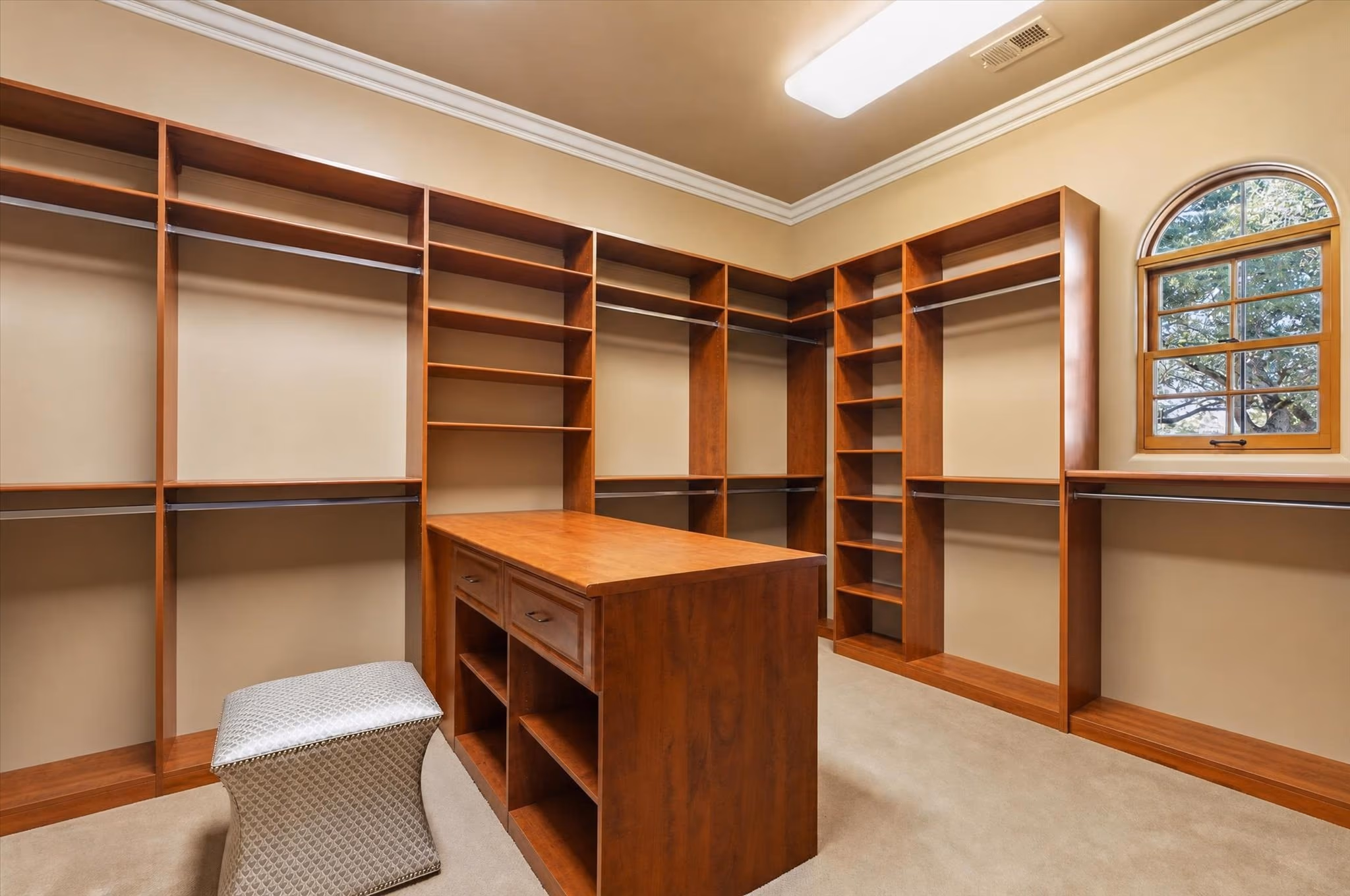 The walk-in closet off the primary suite, fitted out in cherry with a central island of drawers.