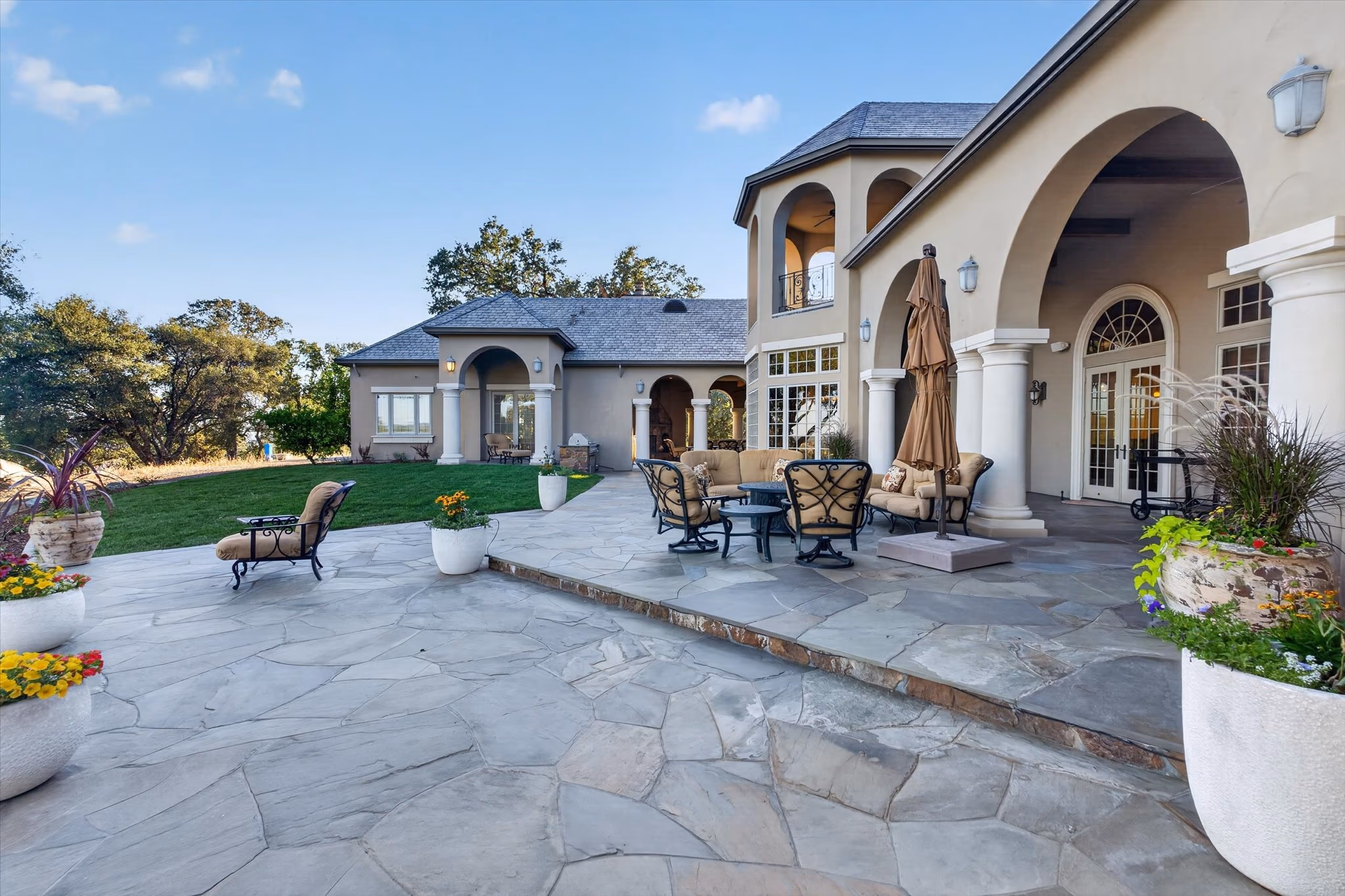 The flagstone terrace behind the main residence, with seating, planters and steps down to the lawn.