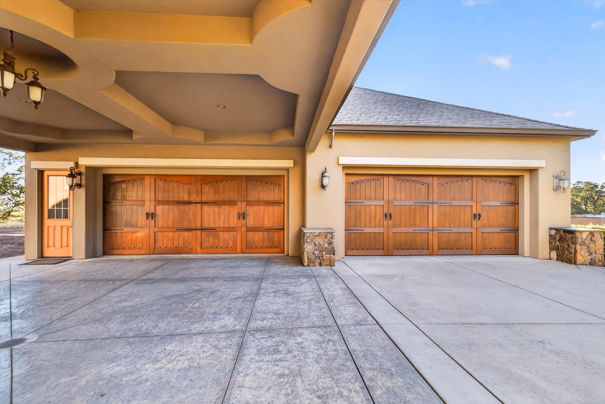 The garage court, with timber carriage doors under a stone and stucco elevation.